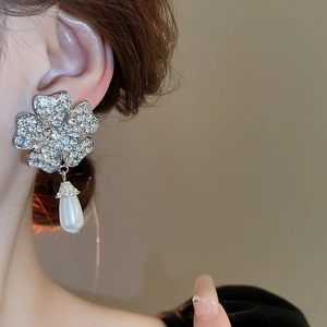 Detail of silver clover earrings with sparkling diamonds and white teardrop pearl drops