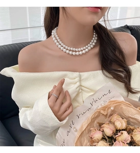 Gros plan d'un collier de perles blanches double rang porté dans un style chic français