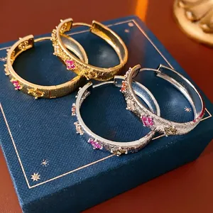 Créoles fleurs plaquées or 18 carats avec pierres en zircon sur boîte à bijoux bleue