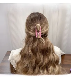 Pink marble acetate butterfly hair claw clip shown on a model with long wavy hair