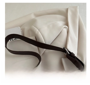 Detail of dark brown leather strap with silver adjustable buckle on a tote bag