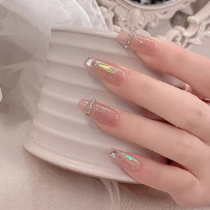 Elegant nude gradient press-on nails with rhinestone accents on a ceramic cup
