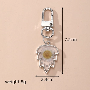 Detail view of leaf-shaped keychain with dried flowers including size and weight specs