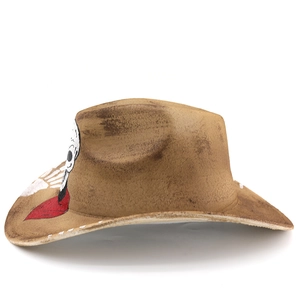 Vintage brown cowboy hat with white skull print and red scarf detail on white background