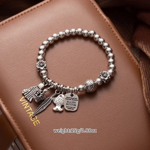 Macro detail of vintage silver beaded bracelet with fish and feather charms on a leather box