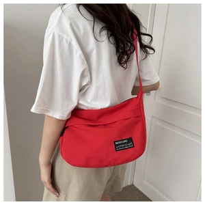 Detail view of the red nylon crossbody bag showing the fabric texture and brand label