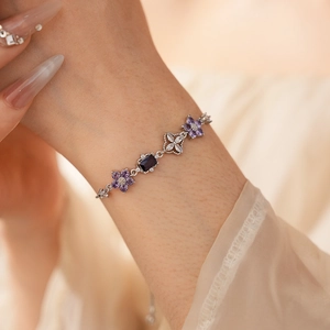 Detailed view of silver flower bracelet with purple zircon stones on female wrist