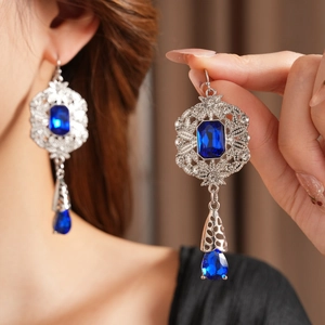Macro detail of vintage water drop earrings featuring sapphire blue gems and silver metal