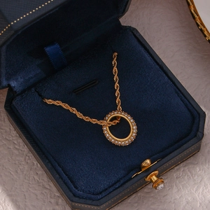 Macro shot of gold twist chain necklace with zircon circle pendant in blue velvet box