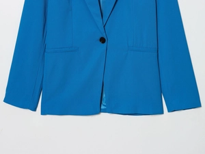 Détail d'un blazer bleu à simple boutonnage avec texture sergée et bouton noir unique