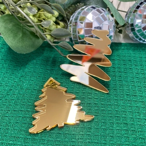 Goldene Spiegel-Acryl-Weihnachtsbaum-Kuchendeko auf festlichem grünem Stoffhintergrund
