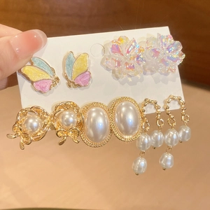 Detailed shot of various enamel butterfly, floral, and pearl stud earrings set