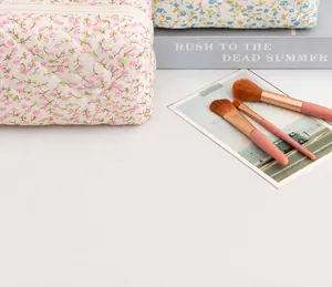Close-up of floral quilted cosmetic bag with makeup brushes and lifestyle props