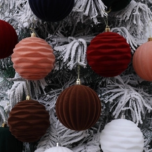 Flocked velvet Christmas balls with wavy patterns hanging on snowy pine tree branches