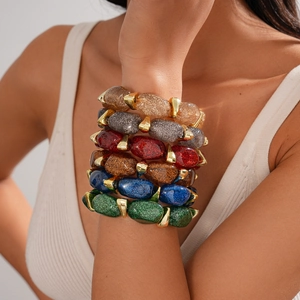Detail of stacked acrylic resin bracelets featuring glitter finishes and metal accents