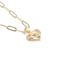 Detail of gold heart pendant with interlocking hands and sparkling zircon stones on chain