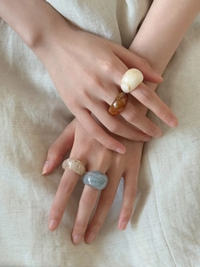 Detailed close-up of amber and beige marble resin rings worn by a model in soft light