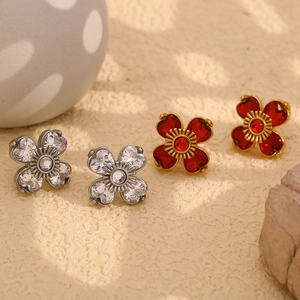 Détail macro de boucles d'oreilles fleur à quatre pétales avec cristaux en forme de cœur