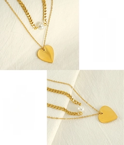 Detail of gold double-layer necklace with heart pendant and pearl on textured fabric