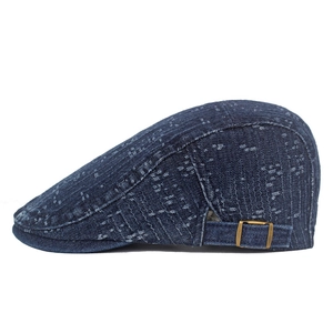 Detail of dark blue denim newsboy cap showing white woven texture and metal buckle