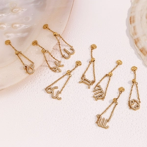 Détail de pendentifs signes du zodiaque plaqués or 18K et zircons sur marbre