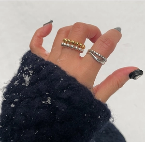 Detail of silver and gold beaded rings stacked for a minimalist winter style look