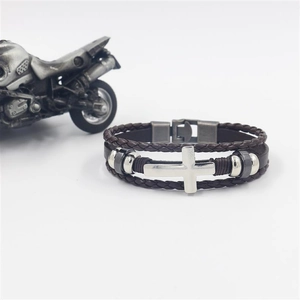Close-up of brown multi-layer braided leather bracelet with silver cross and metal clasp