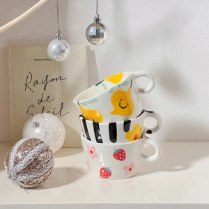 Close-up of three stacked ceramic mugs with hand-painted fruit and flower patterns