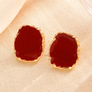 Detailed shot of irregular vintage earrings with red glaze and gold hammered metal texture