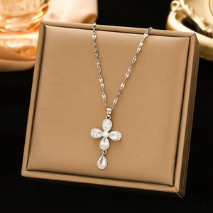 Elegant stainless steel cross necklace with drop-shaped zircon on a gold jewelry box