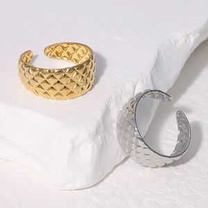 Detailed view of gold and silver quilted stainless steel rings on a stone base
