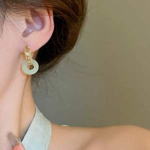 Close-up of model wearing gold-plated circular jade-style earrings with zircon details