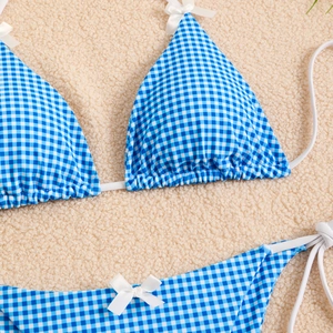 Detail of blue and white gingham bikini with delicate white bow accents and tie strings