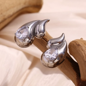 Macro detail of silver double teardrop earrings with pear-cut zircon on a wooden branch