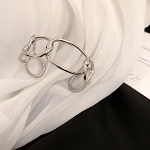 Detailed view of silver chain link open cuff bracelet on elegant white silk background