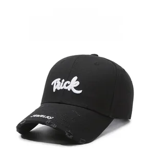 Detail of black distressed baseball cap with Trick letter embroidery and frayed brim edge