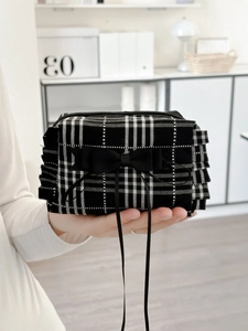 Pochette de maquillage à carreaux avec nœud et bordure à volants tenue en main