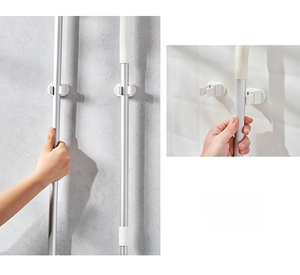 Wall-mounted mop and broom holder showing easy clamp action on tiled bathroom surface