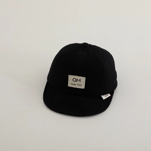 Detail of soft cotton baby baseball cap showing black fabric texture and square brand patch