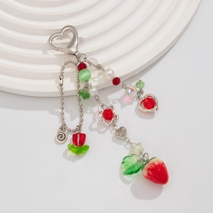 Dettaglio portachiavi con perline, fragola, tulipano e ciondoli a cuore su vassoio bianco