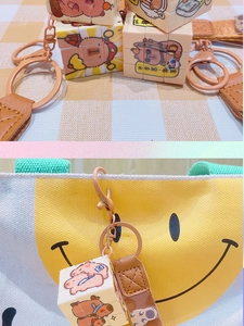 Detail of cartoon character cube keychain attached to a yellow smile canvas bag