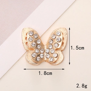 Detail showing dimensions of a 1.5cm by 1.8cm gold butterfly charm with inlaid rhinestones