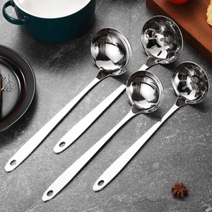Polished stainless steel soup ladles and strainers set on a grey stone surface
