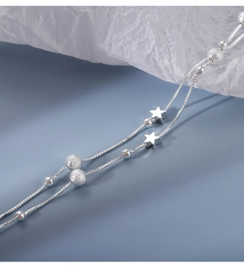 Detailed macro view of silver double-layered box chain bracelet with stars and beads