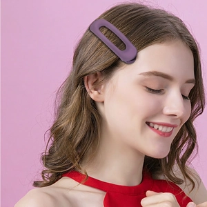 Matte purple hollow oval hair clip for women worn by a model against a pink background