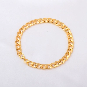 Polished gold curb chain bracelet with lobster clasp on white textured fabric background