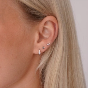 Close-up of triple-set silver earrings with diamonds worn on the earlobe and cartilage