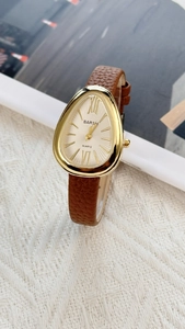 Detailed view of a gold snake-head watch case with a brown textured leather strap