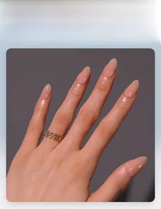Dettaglio di unghie finte a mandorla rosa nude lucide con anello traforato in oro decorato