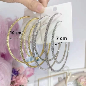 Detail of 7cm and 10cm oversized gold and silver hoop earrings with sparkling rhinestones